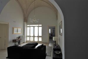 un soggiorno con divano nero e lampadario pendente di La Casa del Mercante a Racale