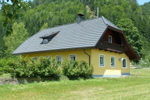 a yellow house with a black roof in a field at Ferienhaus Strasswirt in Jenig