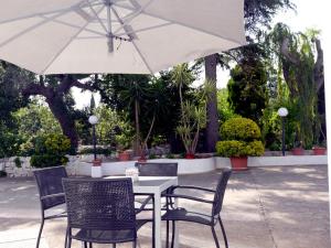 een witte tafel met stoelen en een parasol bij B&B Bell'aria in Monopoli