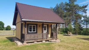 a small house with a porch in a field at Vienkiemis prie Merkinės in Merkinė