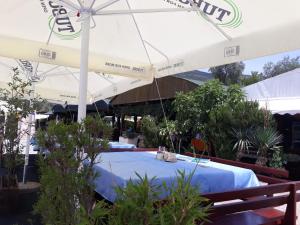a table under a white umbrella in a garden at Apartments Villa-G Lustica in Tivat