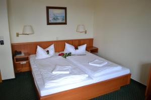 Una cama grande con sábanas blancas y flores. en Hotel Garni Seeschlösschen en Kolpinsee