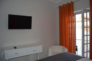 ein Schlafzimmer mit einem Bett und einem TV an der Wand in der Unterkunft Casa do Rochedo in Ribamar
