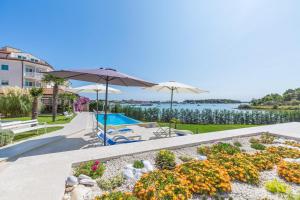 a patio with umbrellas and a garden with a lake at Apartments Fiorido in Medulin