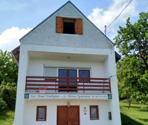 ein weißes Haus mit einem Fenster und einem Balkon in der Unterkunft Szent Ilona Vendégház in Monoszló