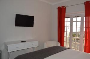 een slaapkamer met een bed, een bureau en een televisie bij Casa do Rochedo in Ribamar