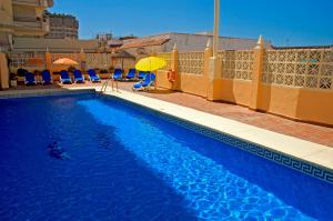 a swimming pool with chairs and an umbrella at Ona Las Rampas in Fuengirola