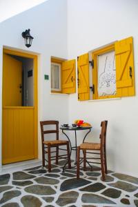 uma sala de jantar com armários amarelos e uma mesa e cadeiras em Ostria em Naousa