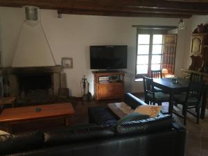 un soggiorno con divano in pelle nera e TV di Masia Can Ninot a Santa Susanna