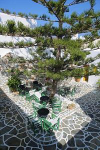 a group of green tables and chairs under a tree at Ostria in Naousa