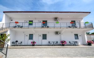 a white building with a balcony and tables and chairs at Bed & Breakfast Delikates in Stojakovo