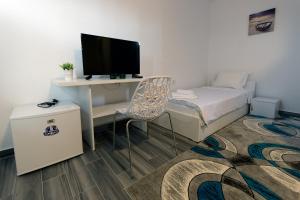 Habitación pequeña con escritorio, cama y TV. en Bed & Breakfast Delikates, en Stojakovo