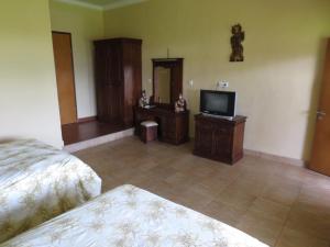 Un dormitorio con una cama y un televisor de pantalla plana. en Nuriani Rooms, en Ubud
