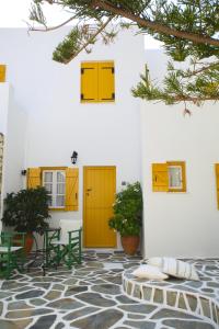 um pátio com portas amarelas, uma mesa e cadeiras em Ostria em Naousa