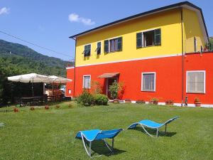 a yellow and red house with two blue chairs in the yard at Varavventura in Riccò del Golfo di Spezia