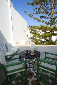 a table and chairs on a balcony with a tree at Ostria in Naousa