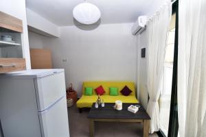 una pequeña cocina con sofá amarillo y mesa en Sunflower Apartments en Kalamaki Heraklion