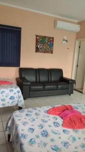 sala de estar con sofá de cuero y 2 camas en Pousada Pesque Park, en Boracéia