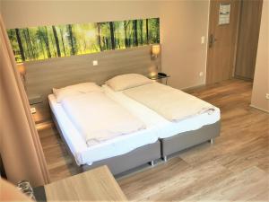 a bed room with a white bedspread and a white comforter at Hotel Scheid in Schriesheim