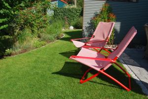 a red chair sitting on the grass in a yard at Claras Strandhuus in Zingst