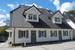 a white house with a black roof at Claras Strandhuus in Zingst