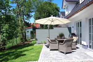 a patio with a table and an umbrella at Claras Strandhuus in Zingst