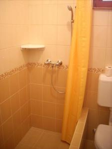 a bathroom with a shower with an orange shower curtain at Dapsy Apartmanház in Jósvafő