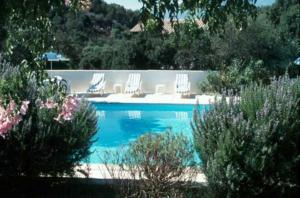 a swimming pool with white chairs and a pool at Résidence Mari di Soli in Porto-Vecchio