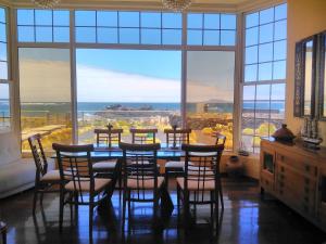 comedor con mesa, sillas y ventanas grandes en Mision Costa en Corralejo