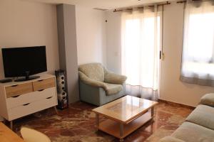 a living room with a tv and a chair and a coffee table at Atico centro Alicante in Alicante