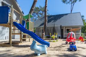 un parque infantil con tobogán y juguetes en la arena en Hubertus Pogorzelica - domki przy plaży, en Pogorzelica