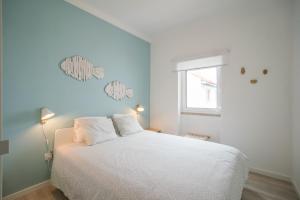 a bedroom with a white bed and a window at Casas da Avó II in Santa Cruz