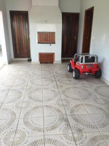 a red tractor parked on a tiled floor in a room at Casa em praia de Garopaba 48- in Garopaba