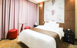 a bedroom with a large white bed and pink curtains at Uljin Grand Hotel in Uljin +40 photos