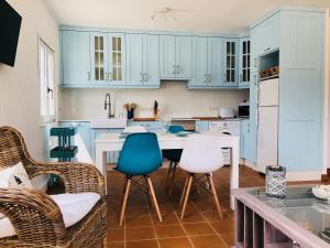 een keuken met blauwe kasten en een tafel en stoelen bij Esteiro Surf Lodge in Santa Marta de Ortigueira