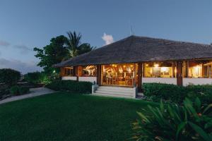 ein Resort mit Strohdach und Rasen in der Unterkunft White Grass Ocean Resort & Spa in Insel Tanna