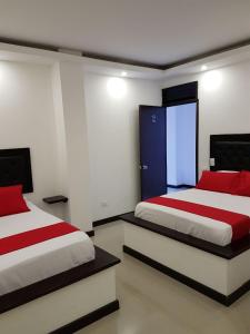 ChinchináHotel Orion的一间卧室，有两张床，床单为红色和白色