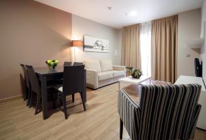 Una sala de estar con una mesa y sillas y un sofá. en Apartahotel & Spa Jacetania, en Jaca
