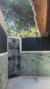 a bathroom with a shower and a stone wall at Jemeluk Beach Bungalows in Amed