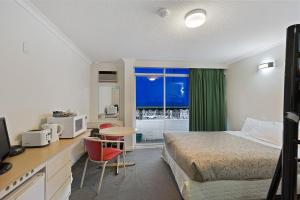Habitación de hotel con cama, escritorio y ventana en Alexander Motor Inn en Melbourne