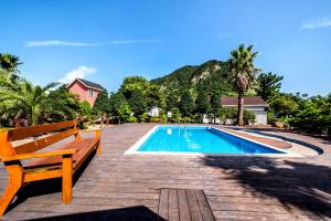a swimming pool with a wooden bench next to it at Mirvill Pension & Resort in Seogwipo