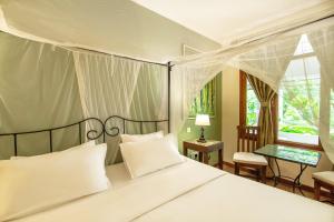 une chambre avec un grand lit avec des oreillers blancs dans l'établissement Mediterraneo Boutique Hotel, à Dar es Salaam