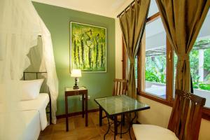 Cette chambre comprend un lit, une table et une fenêtre. dans l'établissement Mediterraneo Boutique Hotel, à Dar es Salaam