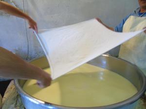 a person is pouring some liquid into a pot at To Exari in Omalos