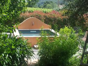 a pool in the middle of a garden with bushes at Les anes de petit jean in Pierrefeu-du-Var