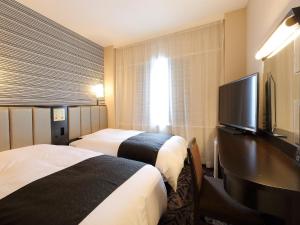 a hotel room with two beds and a flat screen tv at APA Hotel Takaoka-Marunouchi in Takaoka