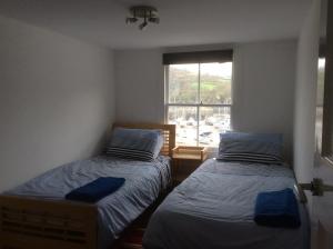 two beds in a room with a window at Olde Lantern Holiday Lets in Ilfracombe