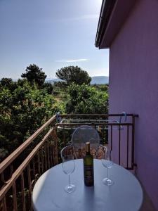 a table with two glasses and a bottle of wine on a balcony at Villa Lory Krk in Krk