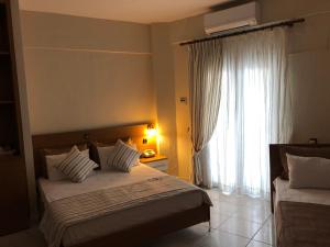 a bedroom with two beds and a large window at Ammouliani Hotel in Ammouliani