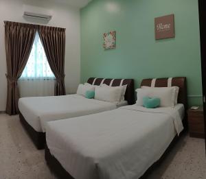 two beds in a hotel room with a window at Austin GuestHouse in Ipoh